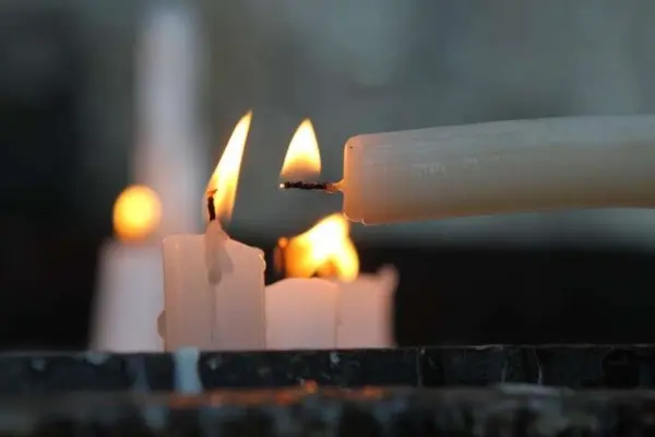 手持白蜡烛引燃其他点燃的蜡烛，背景虚化